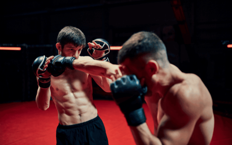 Two fighters engage in MMA, using a variety of martial arts techniques in a cage. The crowd watches as the competitors grapple and strike with intensity